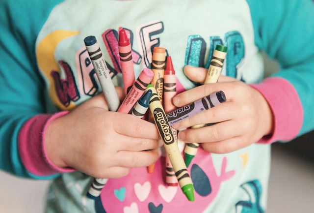 A toddler holding crayons